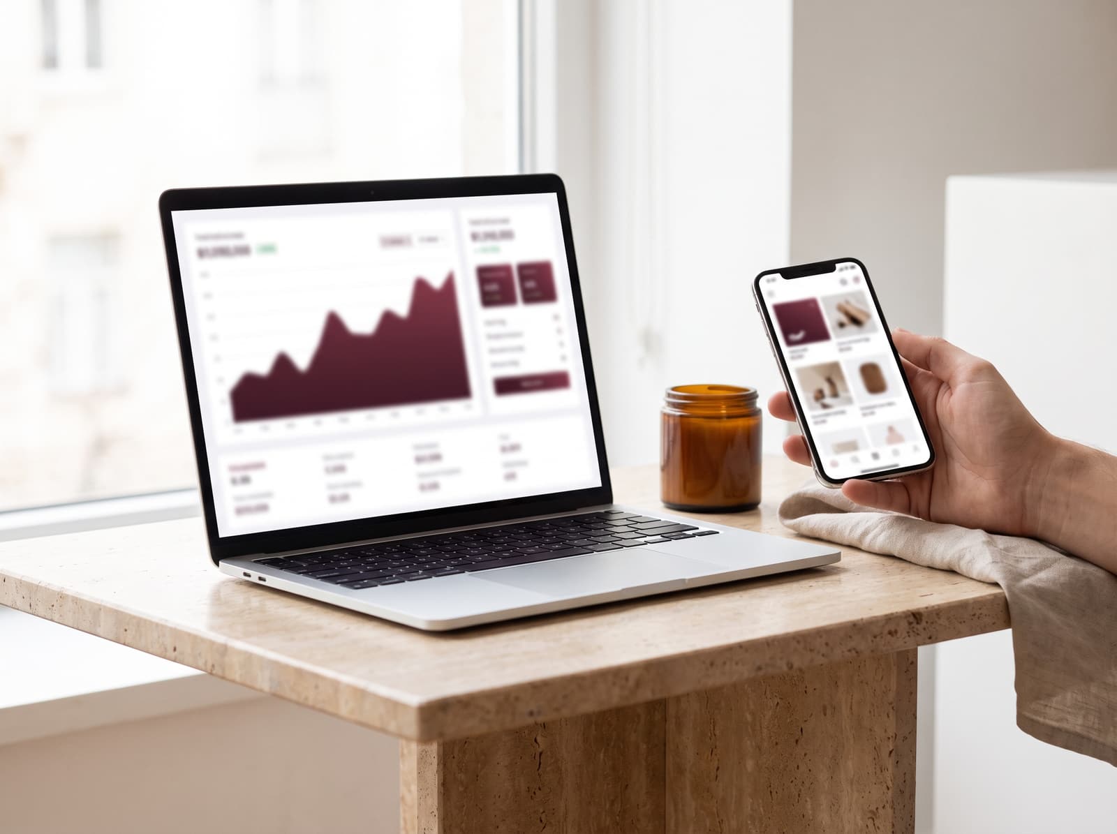 A laptop showing a rising sales chart beside a phone displaying a storefront