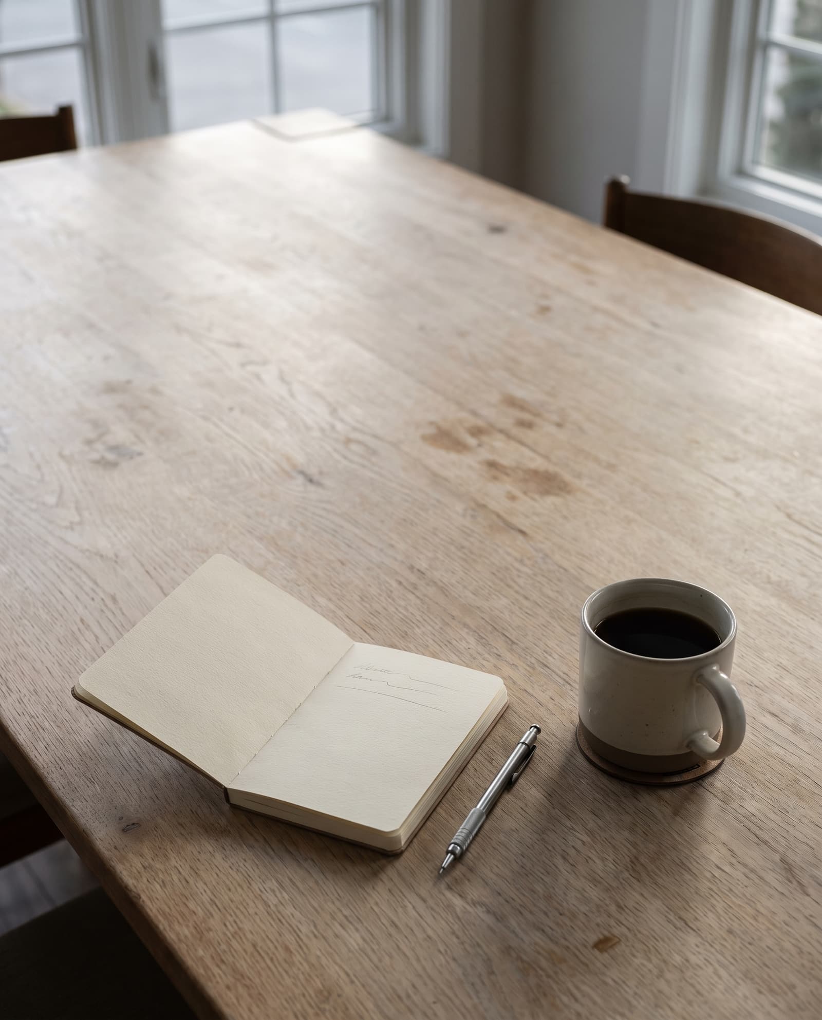 An open notebook and a coffee on a large empty table